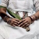 Showing the torso of a woman holding a leaf of which rapé peregun is made