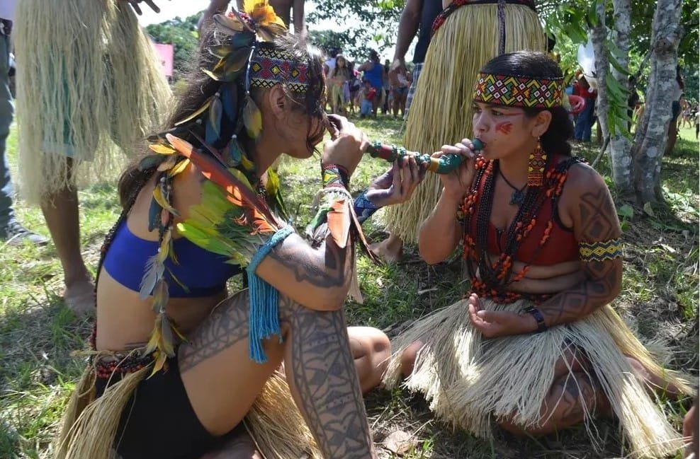 Femme Puyanawa assise sur le sol partageant son rapé, tabac à priser