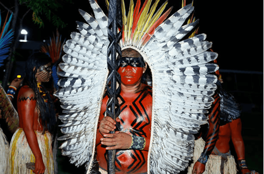 homme yawanawa tenant une lance et portant un cocar (coiffe de plumes)